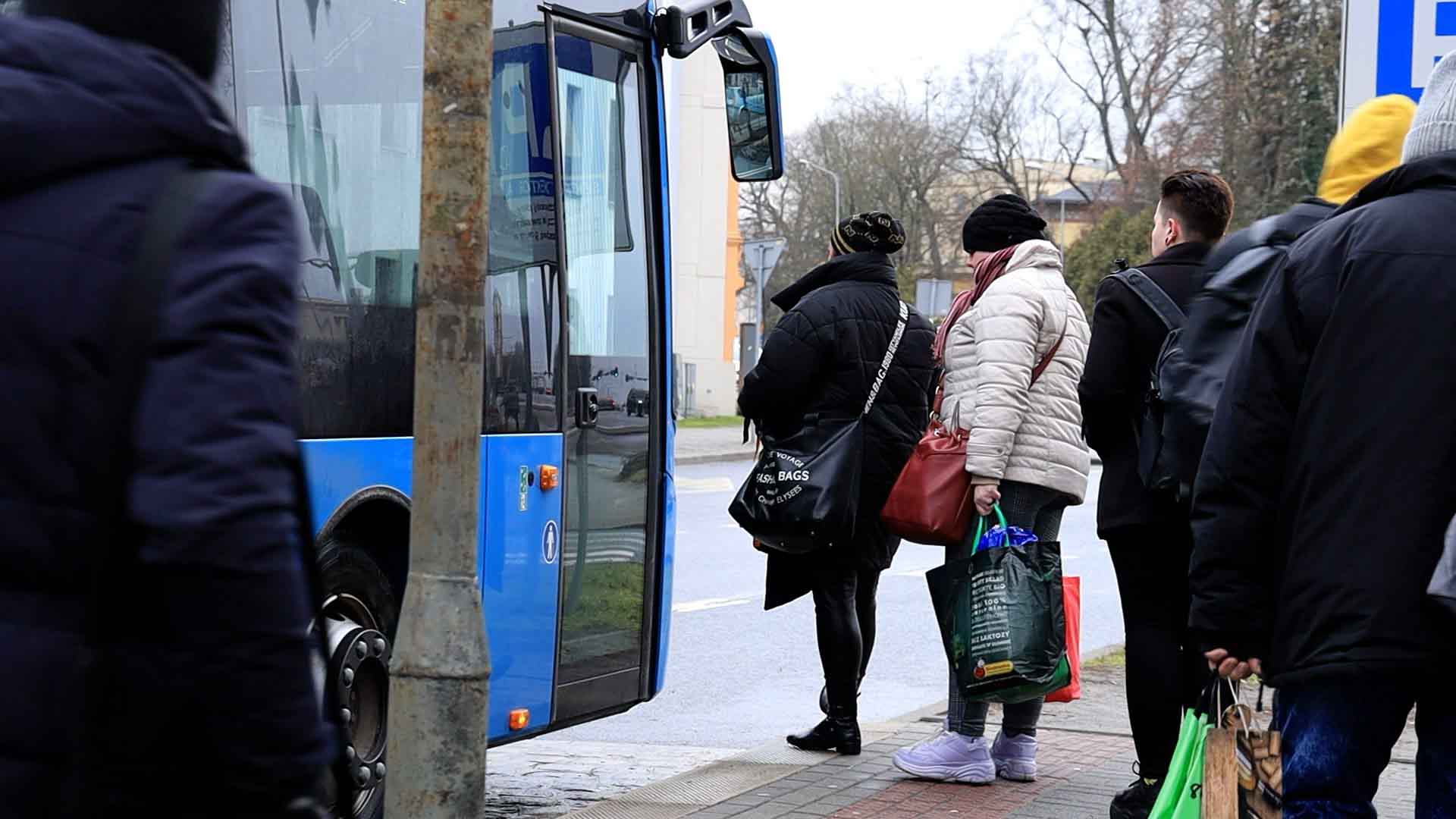 Ludzie wchodzą do niebieskiego autobusu