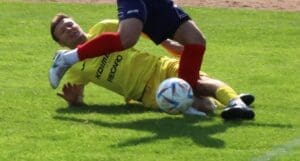 Mężczyzna wchodzący wślizgiem w czasie meczu piłkarskiego