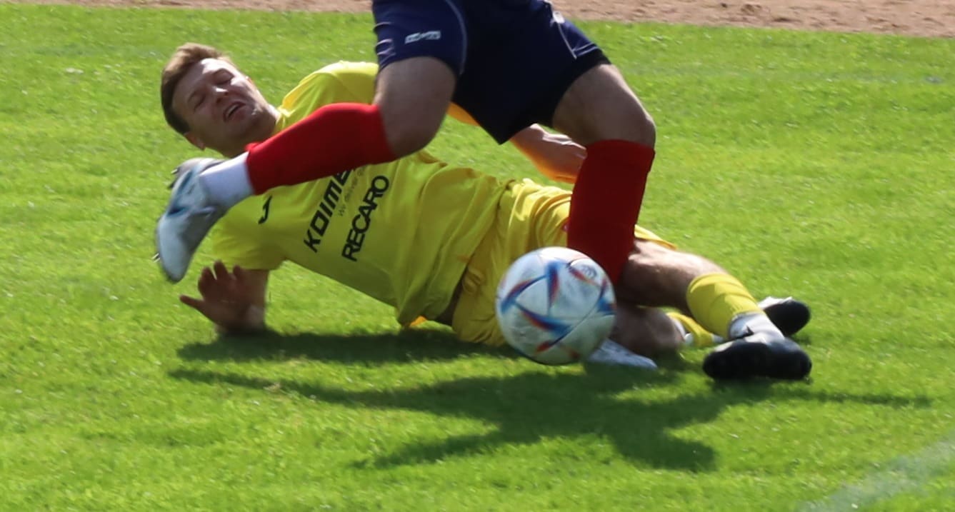 Mężczyzna wchodzący wślizgiem w czasie meczu piłkarskiego