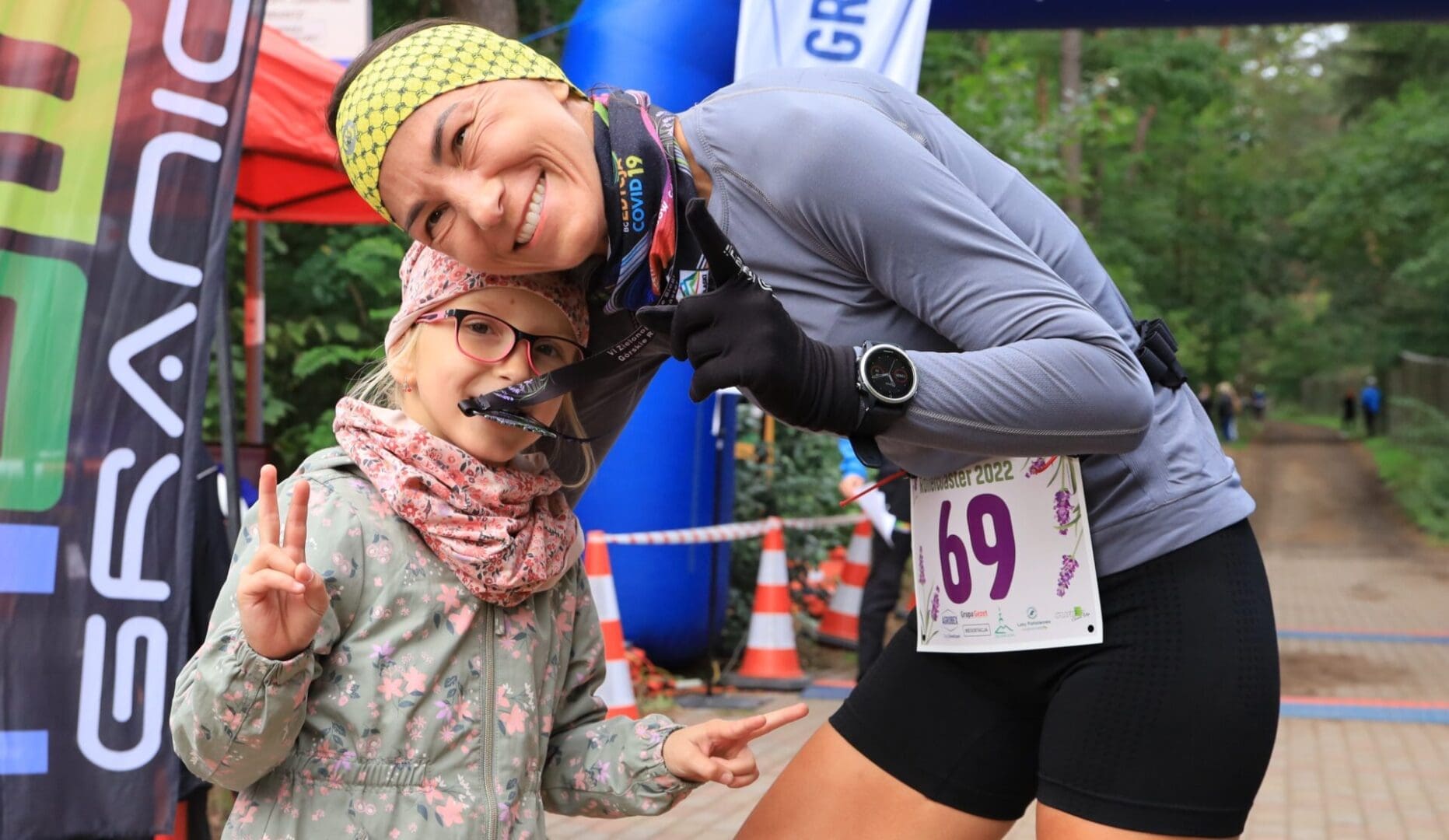 Uśmiechnięta kobieta z dziewczynką gryzącą medal