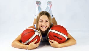 Uśmiechnięta kobieta z dwiema piłkami do koszykówki