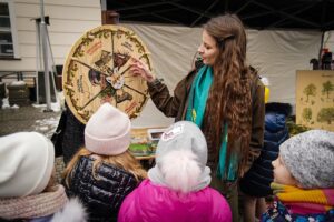 Na zdjęciu dorosła kobieta prowadzi zajęcia dla grupy uczniów