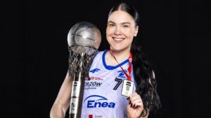 Uśmiechnięta kobieta w sportowym stroju z pucharem i medalem