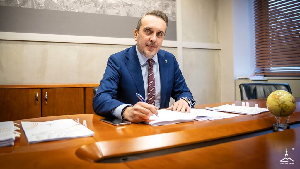 Mężczyzna w garniturze podpisujący dokumenty