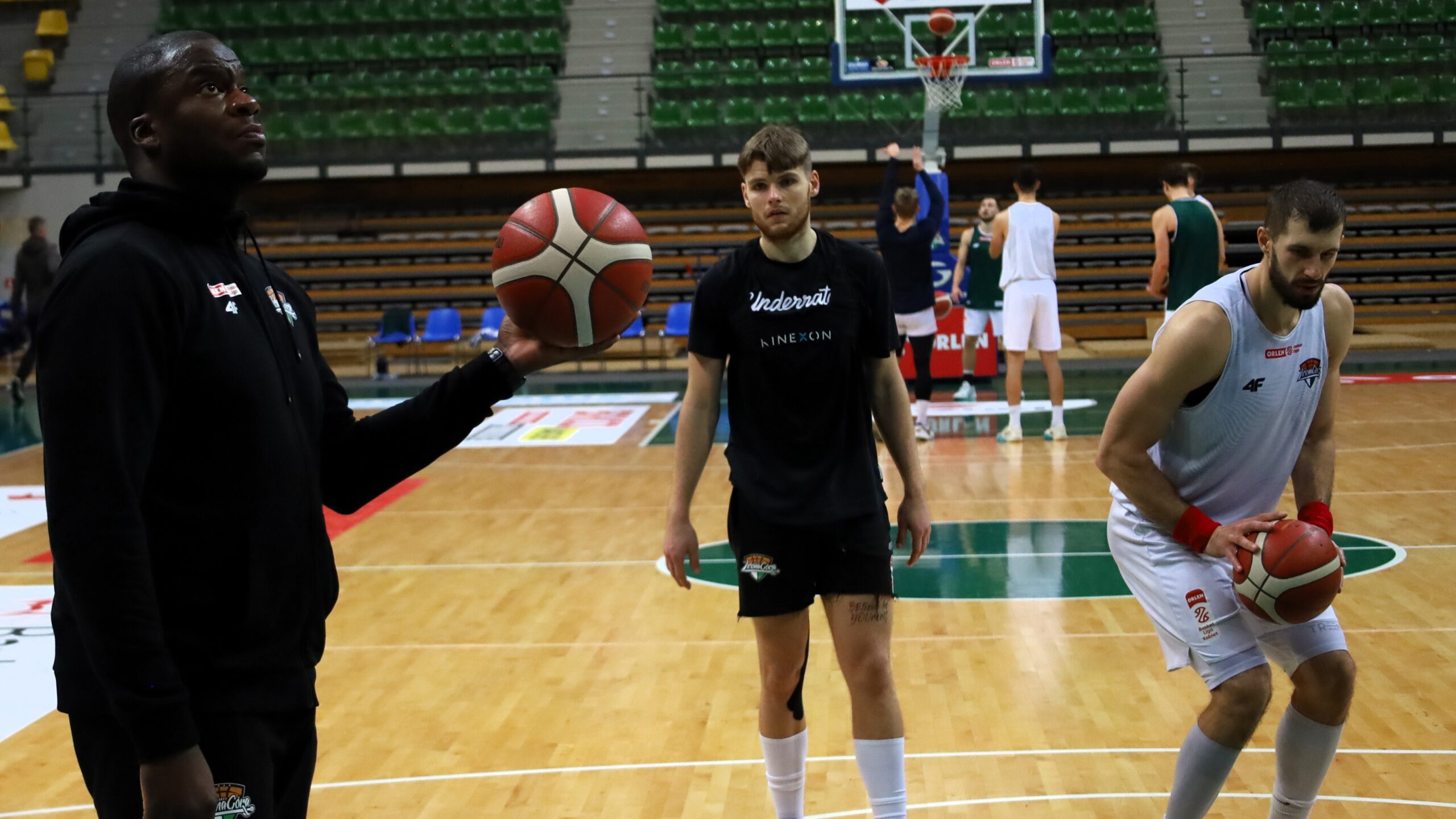 Trzech mężczyzn w sportowych strojach i z piłkami do koszykówki