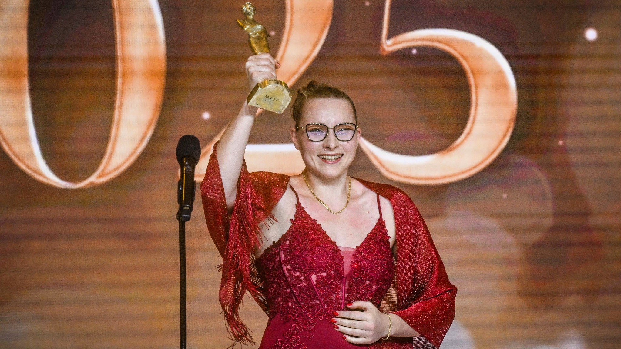 Usmiechnięta kobieta ze statuetką w ręku